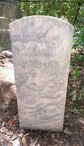 A restored granite headstone with crisp lettering